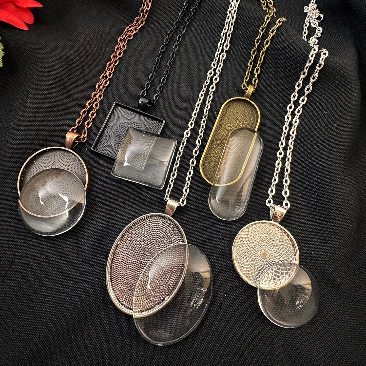 Collection of various necklaces with different pendants for jewelry making on a black fabric background