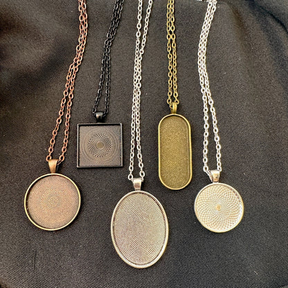 Set of five necklaces with various pendant designs on a dark fabric background